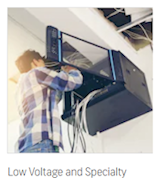 Low Voltage and Specialty – technician wiring equipment in a ceiling-mounted enclosure
